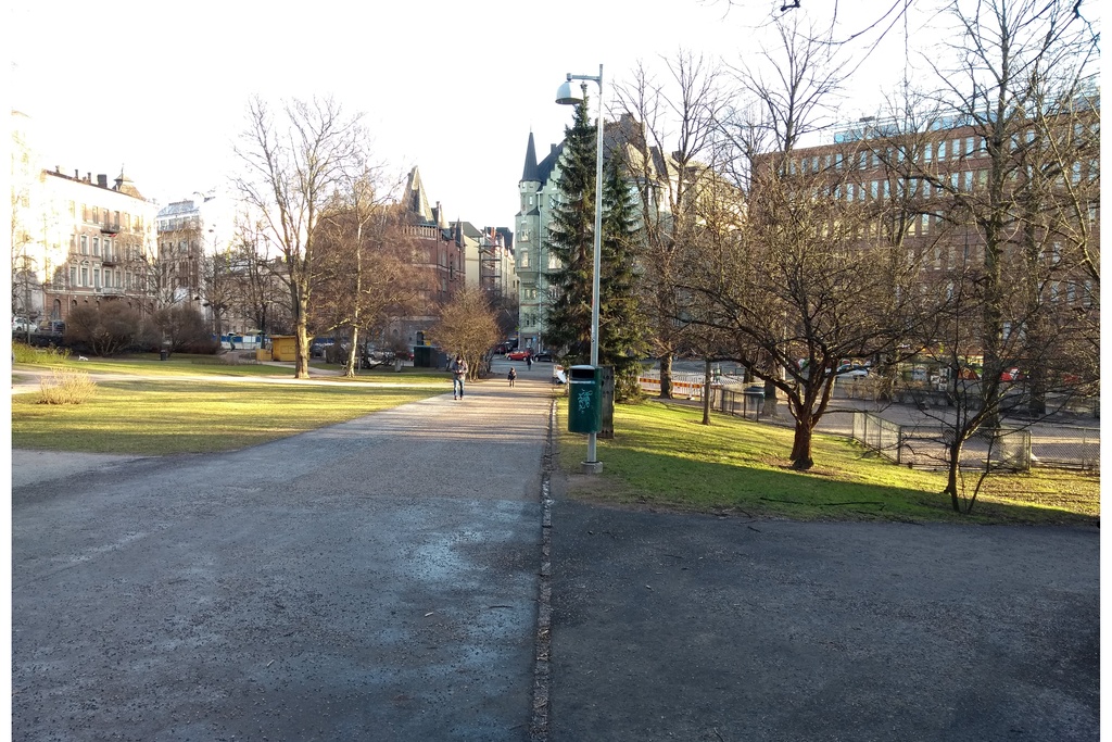 Katajanokka. Näkymä Kanavakadulta itään Satamakadun suuntaan, nykyisin paikalla on Tove Janssonin puiston puistokäytävä. Vasemmalla luminen Katajanokan puisto. Taustalla keskellä Satamakatu 5:n kerrostalo Luotsikadun ja Kruunuvuorenkadun kulmassa. rephoto