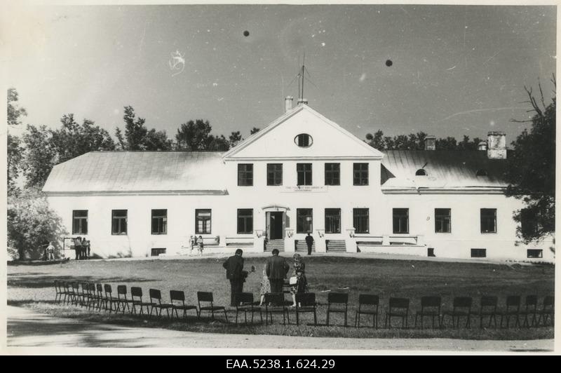 Front of the main building of the SIPA manor with a sign "Hellocome to home researchers and nature friends!". Two men and women on the front and the chair