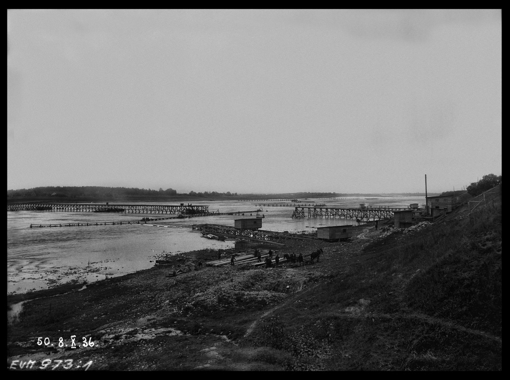 Pirmā pagaidu koka tilta būve pār Daugavu Ķegumā, spēkstacijas būvvietā. 1936.gada 8.oktobris - From 1936 until 1940, the remarkable Latvian cameraman and photographer E. Kraucs (1898 – 1977) regularly, 1 – 2 times a week, photographically documented the construction of the Kegums power plant.