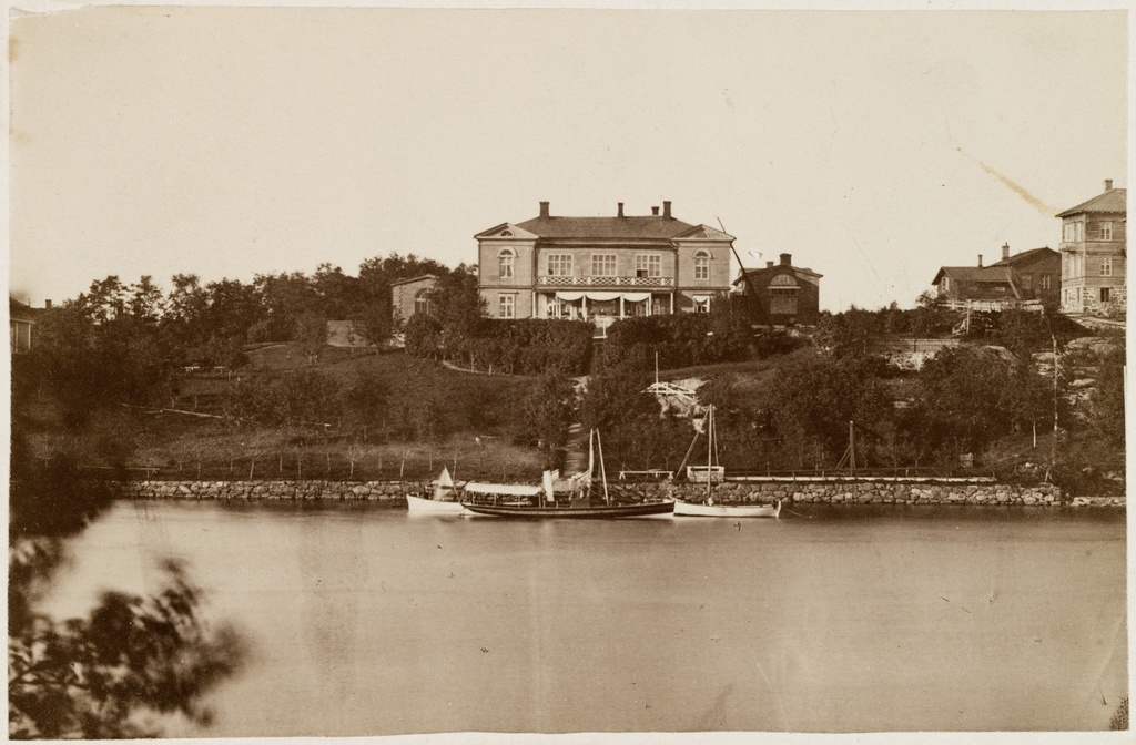 Huvila n:o 13 Itäisessä Kaivopuistossa, ennen paloa elokuussa 1879. Vanha osoite Huvilatie 13, nykyinen Kalliolinnantie.  Kuvan etualalla meri ja laituri, jossa  veneitä.
