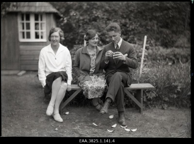 Two young women and a man sitting on a garden bench