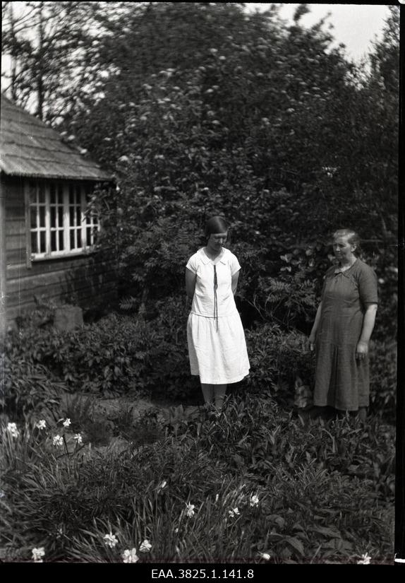 Two women standing in the garden between the flower fences
