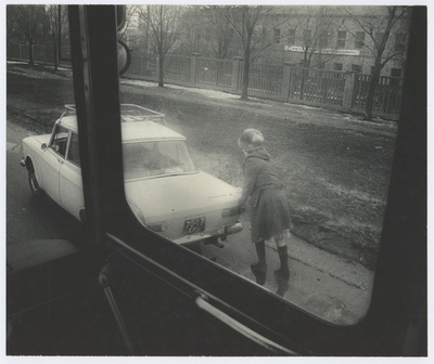 View through the car window: a woman pushing the car.  duplicate photo