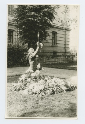 Broken monument layer at the Real School. In the form there are blue white flags, the foot of the pillar is covered with flowers.  duplicate photo