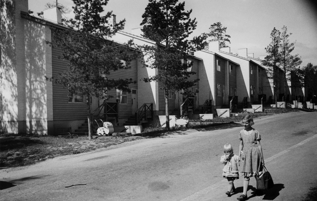 Länsi-Herttoniemi, Karhutie 26. Rivitalo. Kaksi lasta kävelee käsikädessä kuvan reunassa. Rivitalon edessä ulkona kaksi lastenvaunua.