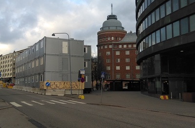 Rakennuksia ja aidattu puutavaran varastointialue nykyisen Ympyrätalon paikalla. Oikealla Porthaninrinne 1 ja 3. Vasemmalla Toinen linja 5 ja Porthaninkatu 1. Taustalla Arena talo. rephoto