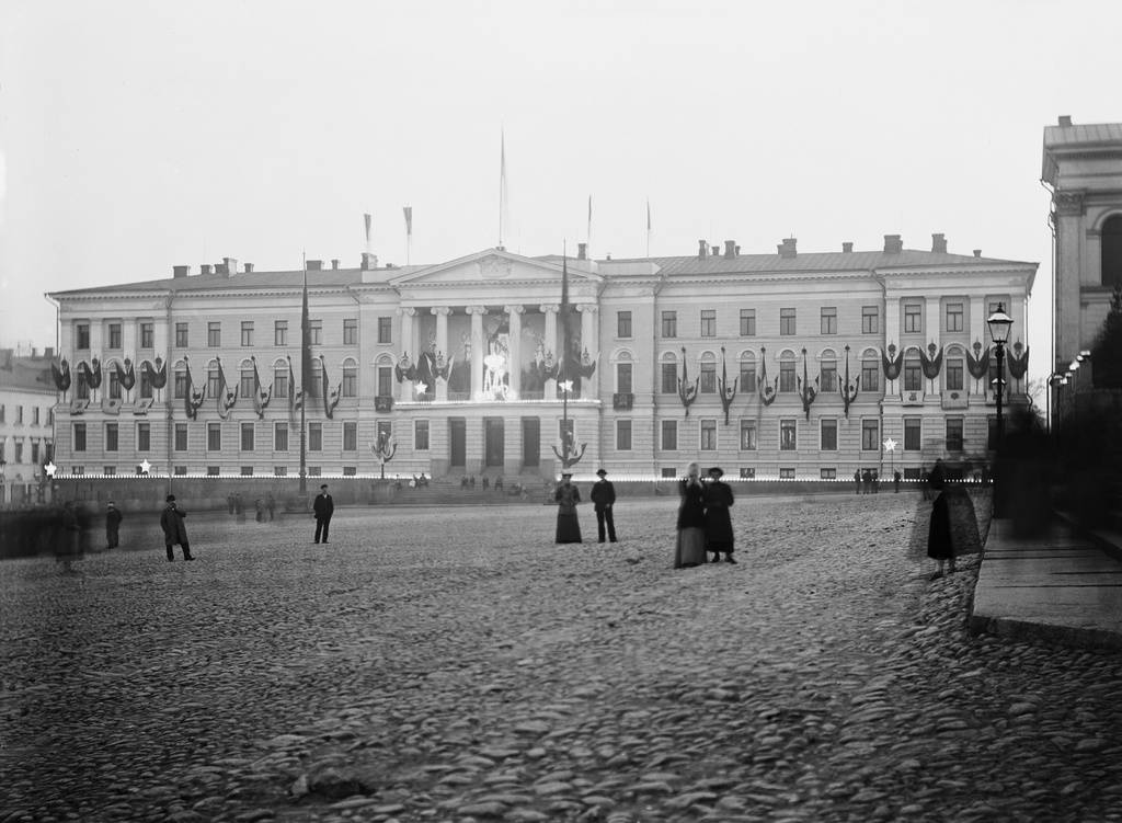 Yliopiston päärakennuksen julkisivu koristeltuna ja juhlavalaistuna keisari Nikolai II :n kruunajaispäivänä