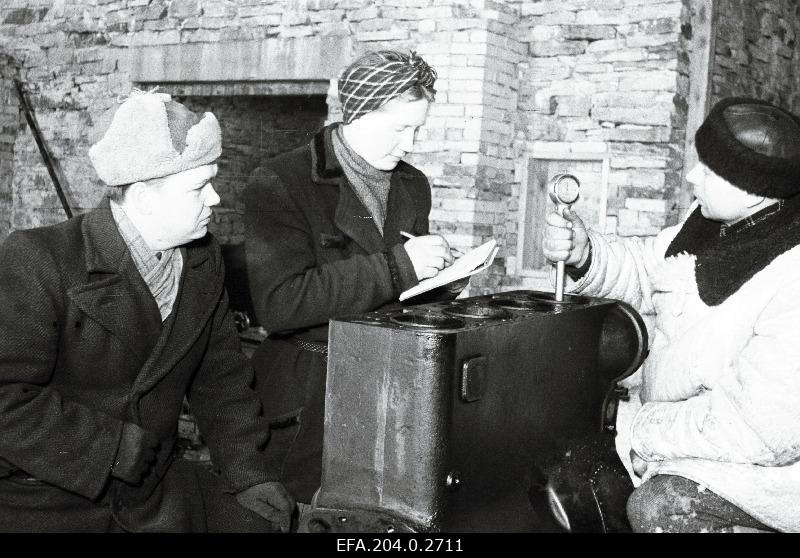 Sipa masina-traktorijaama direktori asetäitja poliitalal R. Rooste, vanemmehaanik I. Kaldari ja kontrollmehaanik A. Rooste NHT-i mootori silindrit kontrollimas.