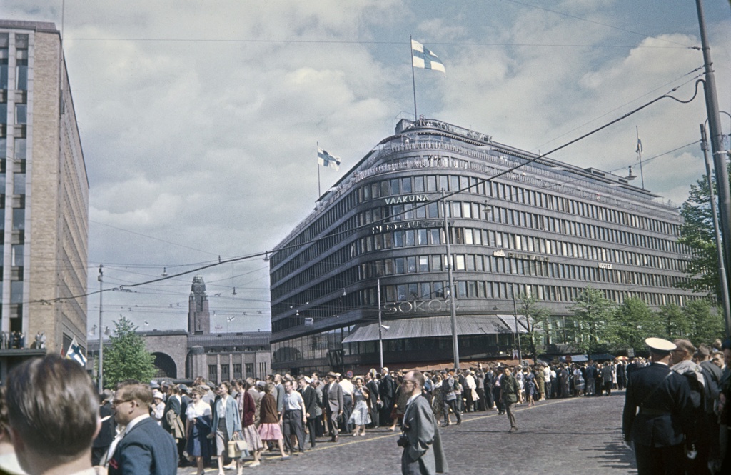 Mannerheimintie 9.- Postikatu 1, 2. Yleisöä katsomassa Mannerheimin ratsastajapatsaan paljastusta. Taustalla Sokos-tavaratalo ja Rautatieasema, vasemmalla Postitalo.