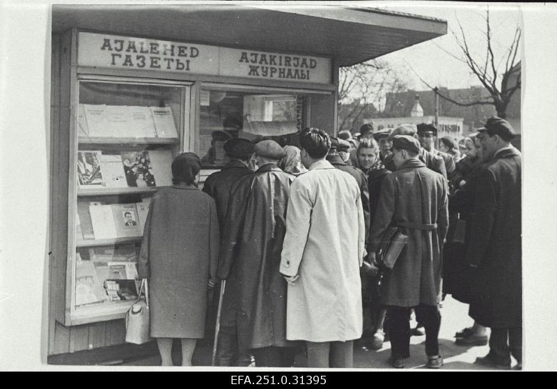 People buy newspapers in front of the newspaper kiosk.