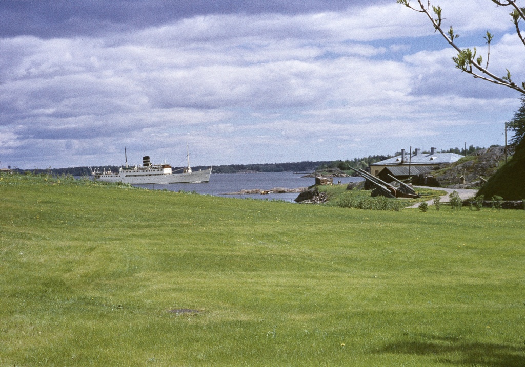 Suomenlinna, Susisaari. Nurmikko Vallisaaren muistomerkin alapuolella (vanha salmi). Taustana Sotamuseon tykkejä ja varastorakennus (A 5).