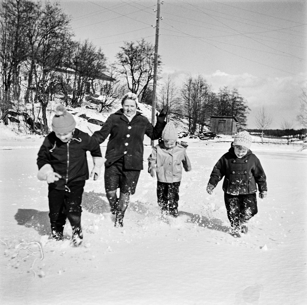 Hilkka Hurskainen ja hänen lapsensa juoksevat tietä pitkin Vallisaaressa. He potkivat mennessään lunta, joka lentää ilmassa. Tie kulkee Kuolemanlaaksossa. Oikealle taustalle jää Torpedolahden laituri.
