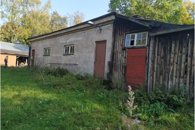 Paloaseman palokalustovaja Vallisaaressa. Siinä säilytettiin aikanaan T-mallista Fordia, kuorma-autoa ja hevosvetoisia kärryjä. Keskimmäisestä ovesta kuljettiin kahden hevosen talliin ja viereisestä punaisesta ovesta hevosten rehu- ja heinävarastoon. Pihapiiriin kuuluu myös vasemmassa reunassa näkyvä puusepänverstas. Valokuva on otettu aurinkoisella säällä. rephoto