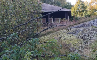 Opettaja Juha Alanen ja koululaisia mäenrinteessä Vallisaaressa. Taustalla näkyy vuonna 1958 saarelle valmistunut koulurakennus. Ryhmäkuva on otettu keväisessä auringonpaisteessa. rephoto