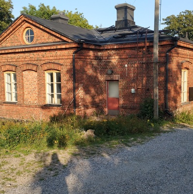 Vallisaarelaisia saaren luotsitalon pihapiirissä. Kaksi miehistä on sotilasunivormussa. Toisella naisista on sylissään pieni lapsi. Taustalla näkyvä tiilirakennus on luotsitalon sauna- ja pyykkitupa. rephoto