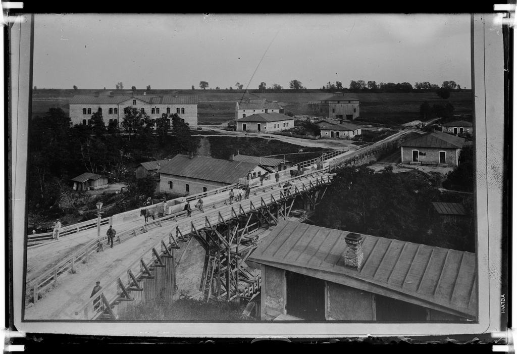 View of the bridge, behind the left arm of boys, the first homes of the workers and the middle of the men's common room, the so-called star tower (wood). On the left of the bridge, the workers' dwelling of the so-called subpohlaka (the Poles built it under the shore), the bridge sees a horse-train. The front right is a sprayer. Behind the right there is a horse railroad leading to Kunda Manor.