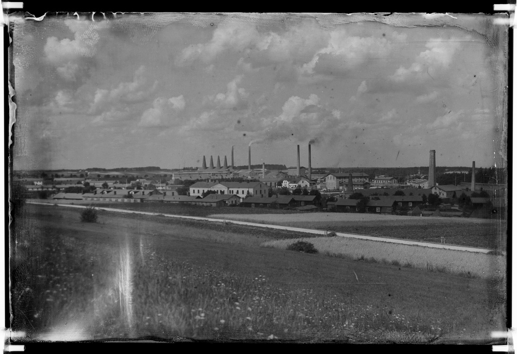 View of Kunda Hiiemäe Malla from the end. On the front of the so-called red houses, these were disposable workplaces with wooden linings painted with Swedish red. In the back of the arm of the boys. On the horizon left the ovens of the third factory, in the middle of the boilerhouse, and on the right are the preserved gardens of the first and second factory.