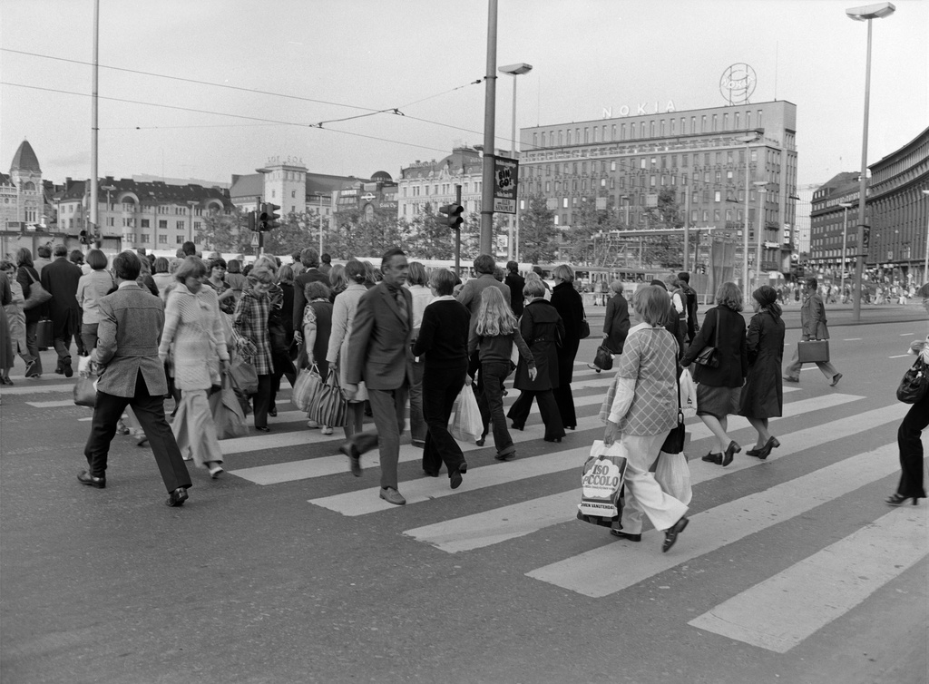 Jalankulkijoita ylittämässä katua Kaivokadun ja Keskuskadun risteyksessä. Taustalla Rautatientori, Kaisaniemenkatu, Mikonkatu.