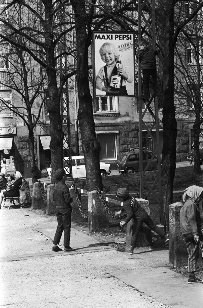 Fleminginkatu. Poika kiipeämässä Fleminginkadun varrella Kallion kirjaston vieressä olevaan lyhtypylvääseen, jossa Maxi Pepsi -mainos. Toinen poika heittelee savipalloja.