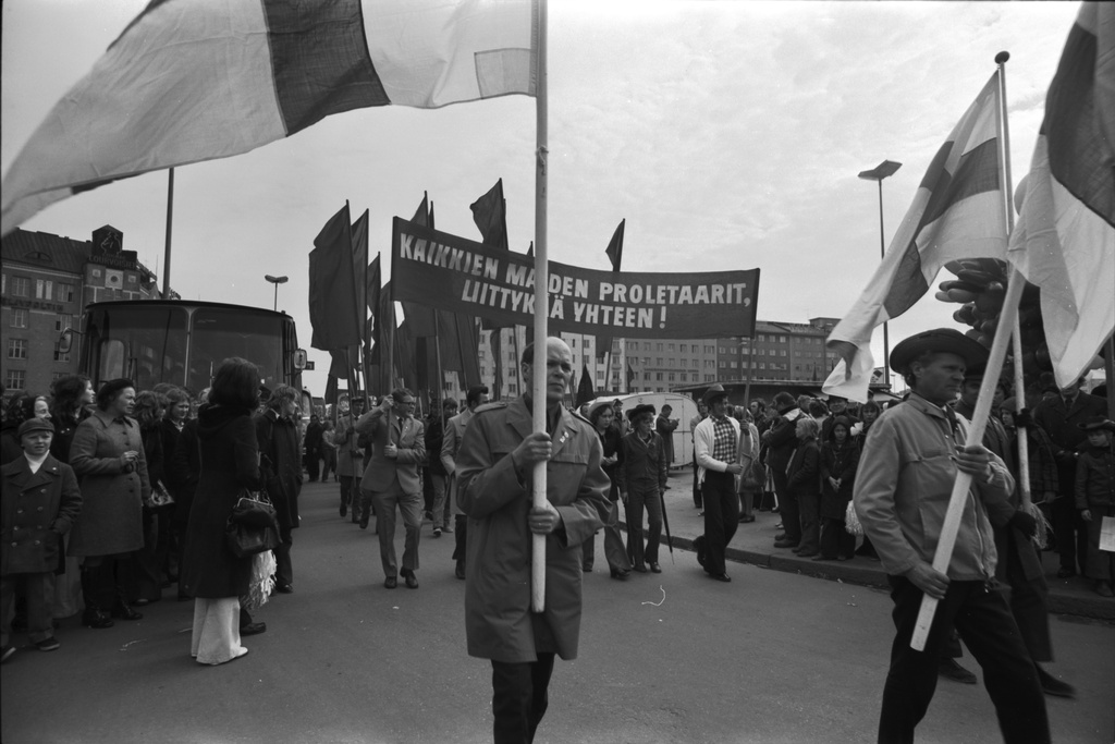 Hakaniementori. Työväen vappukulkue lippuineen lähdössä liikkeelle Hakaniementorin laidalla 1.5.1972. Banderollissa teksti: Kaikkien maiden proletariaarit, liittykää yhteen!