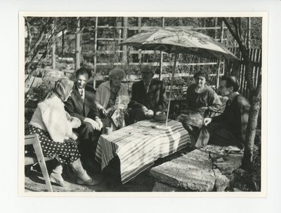 Tuglased külalistega aias päikesevarju all  similar photo