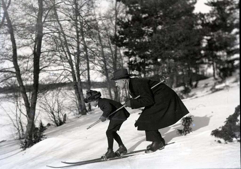 Skiing on the socks, son and father skiing the mountain down, son skiing and rods, winter clothes, snow on the ground