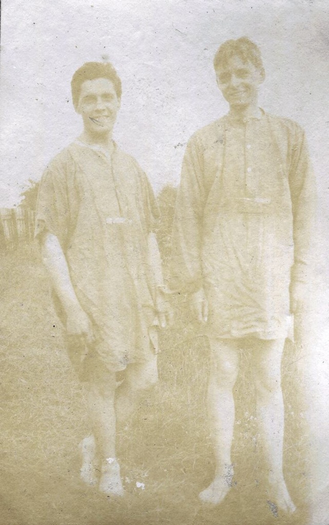 Two males standing in long shirts, 1915