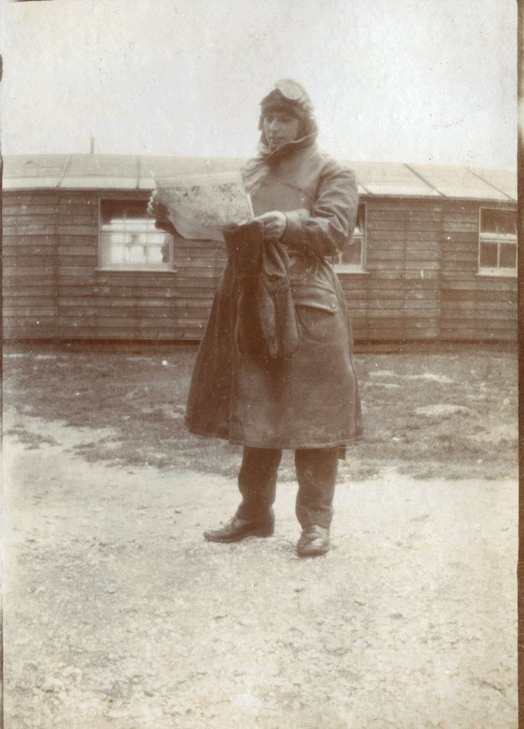 Sgt Van der Linde, in flying gear looking at a map, outside a hut, Beaulieu, 1918