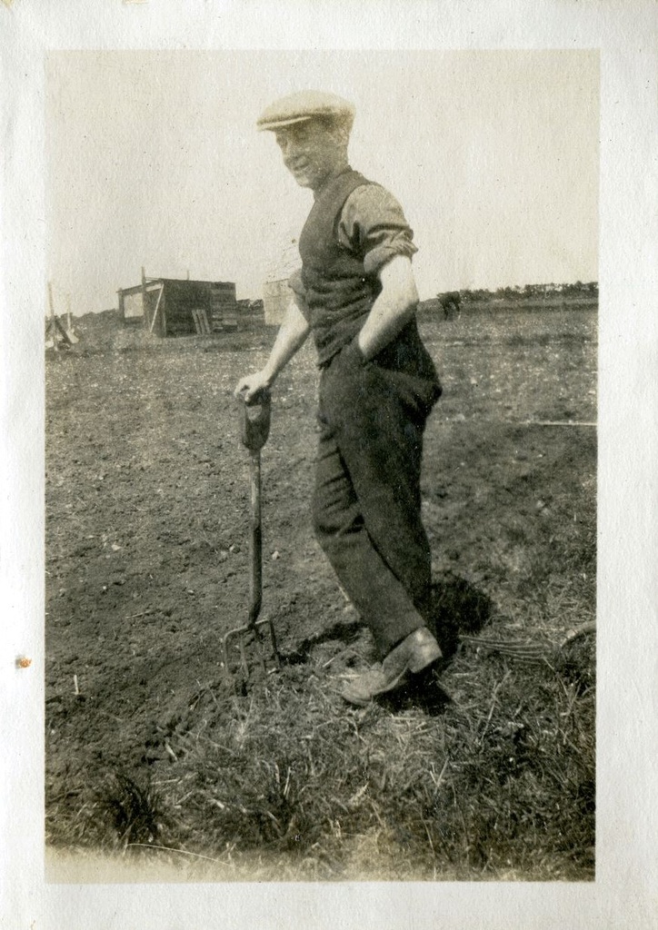 Man in a field learning on a fork