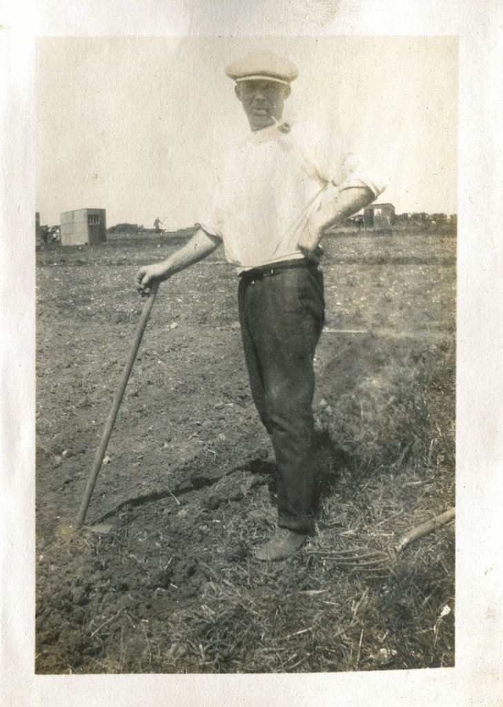 Man in a field learning on a hoe