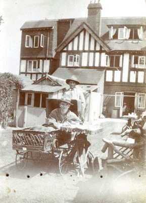 Man in a wheelchair with another man behind him, outside Ye olde Tea Shoppe, Brockenhurst 1918  similar photo