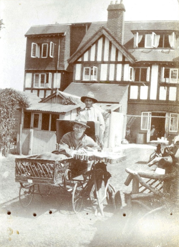 Man in a wheelchair with another man behind him, outside Ye olde Tea Shoppe, Brockenhurst 1918