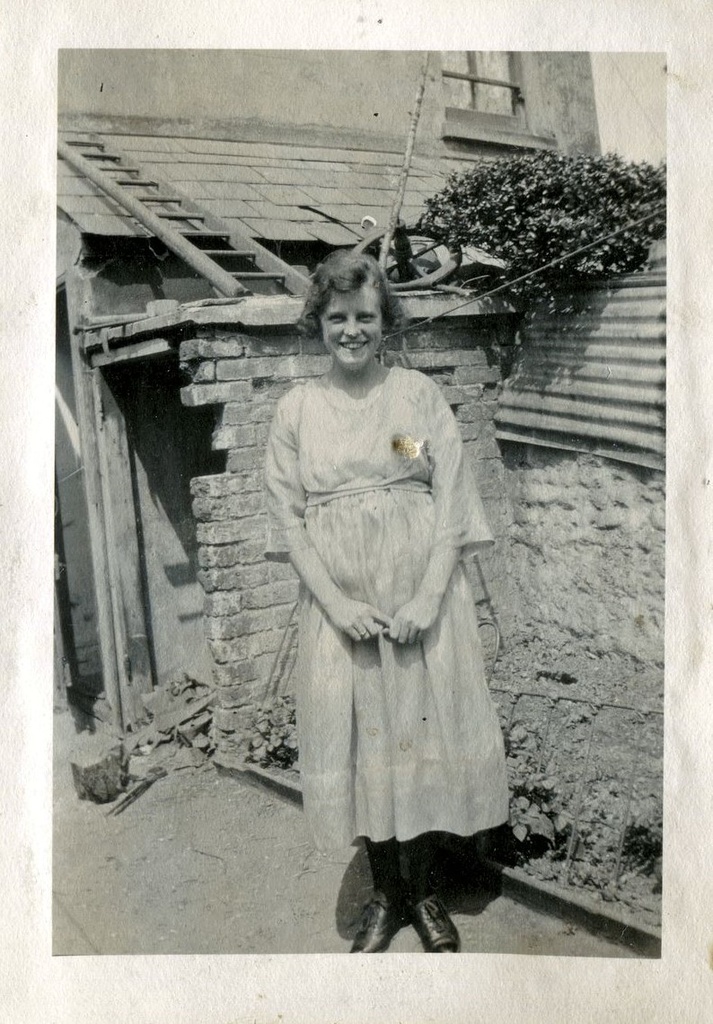 Woman standing in front of a house with a ladder on the roof, June 1922, Hove