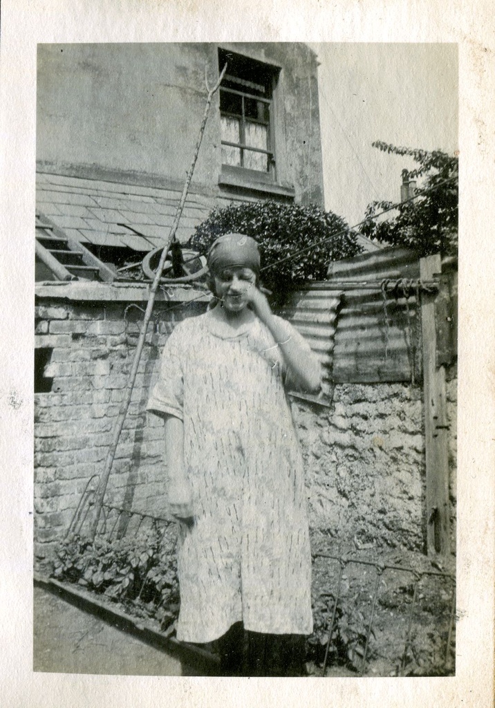 Woman standing in front of a house with a ladder on the roof, June 1922, Hove