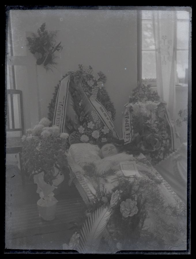 Matusefoto, naine avatud kirstus, kirst ümbritsetud lillekimpudega.