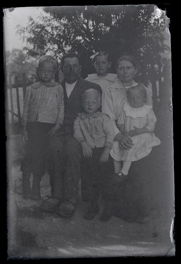 Grupifoto, kaks vanemat ja neli last, taustal näha lippaed.