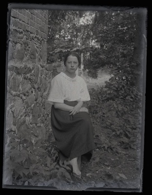 Istuva naise portree, pildistatud hoone kiviseina kõrval.  duplicate photo