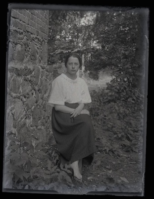 Istuva naise portree, pildistatud hoone kiviseina kõrval.  duplicate photo
