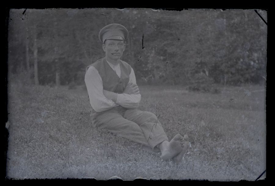 Paljasjalgne mees istub murul.