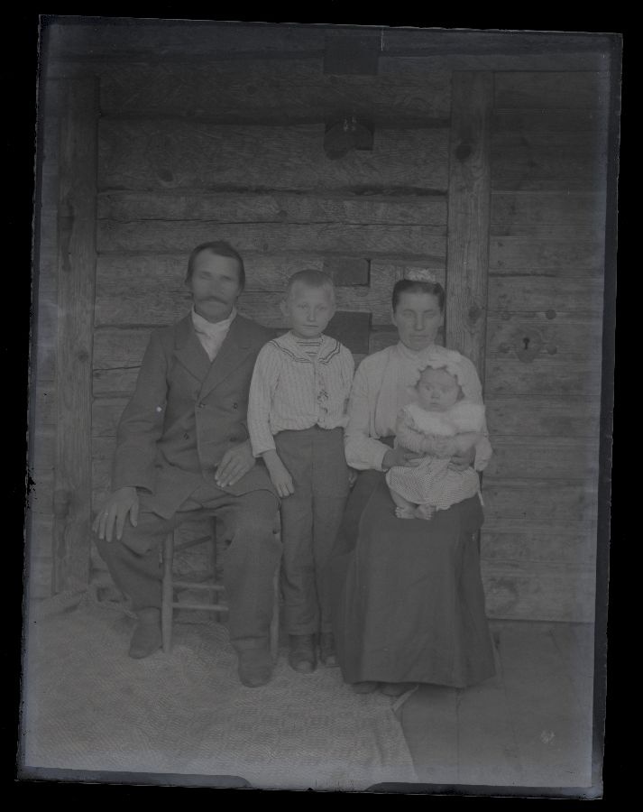 Perepilt, vanemad koos kahe lapsega, pildistatud maja ees.