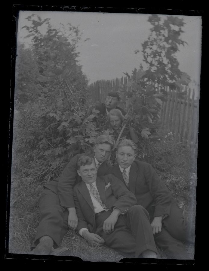 Grupifoto, neli meest ja üks tüdruk aias, vasakul lippaed.