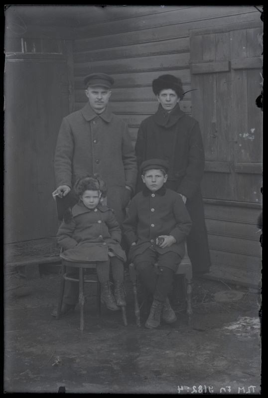 Isa, ema ja kaks last maja ees