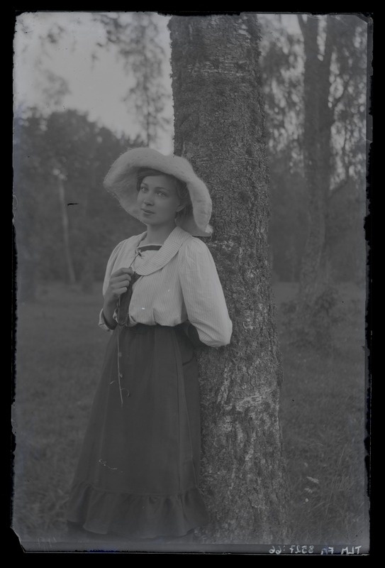 Portreefoto, naisfiguur kübraga toetumas kasetüvele, umbes 1917. aastast.