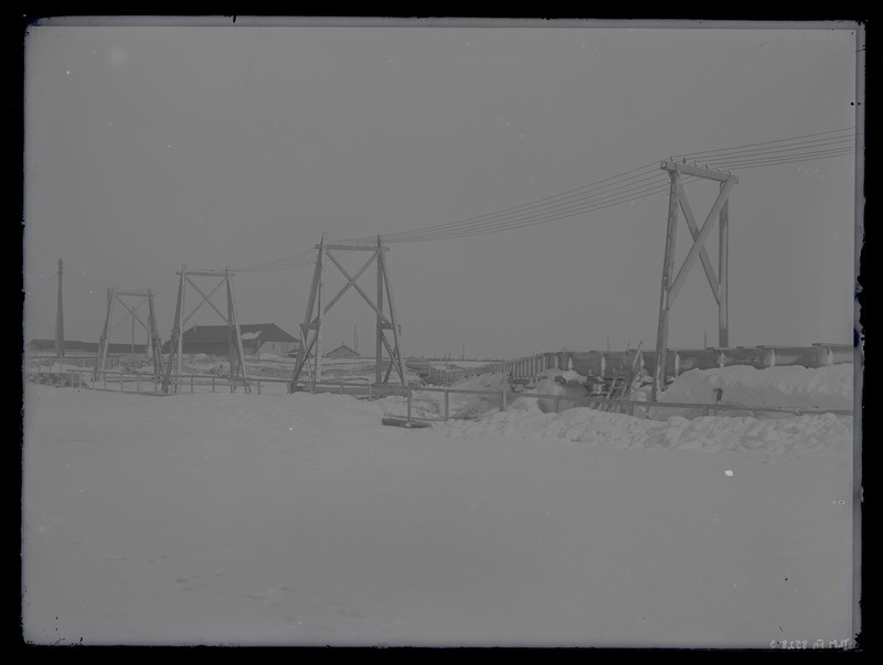Talvine vaade mingile rajatisele - silla- või tammiehitusele, esiplaanil elektriliin, umbes 1910. aasta.
