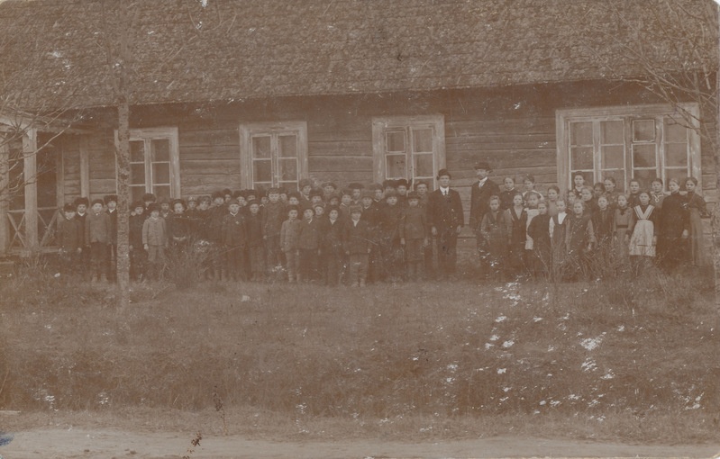 Grupifoto: VAna-Roosa Miku kooli õpilased ja õpetajad koolimaja ees õues. Keskel vasakul õpetaja A. Määrits.