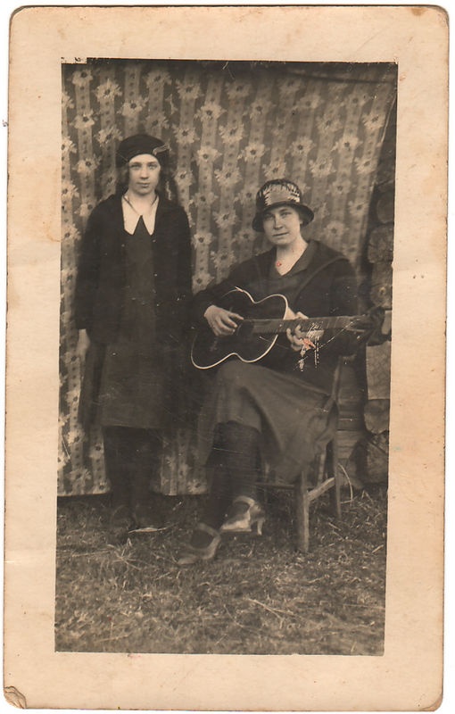 Naine istub kitarr käes, tütarlaps seisab