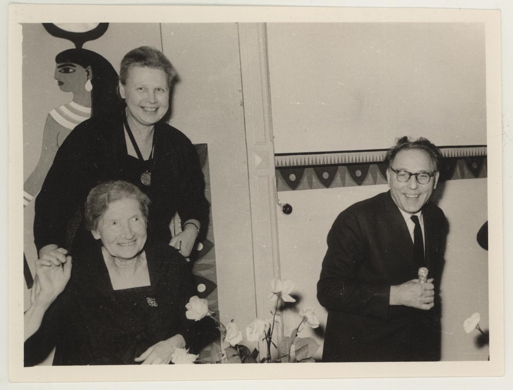 Peavarahoidja Tui Koorti 50. a. juubeli tähistamine 12. apr. 1964. Enne šampanjapudeli avamist. Tuui Koort oma ema selja taga, kunstnik Alfred Kongo.