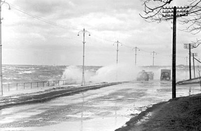 Storm. Seawalls hit the Pirita road. Cars drive through waves.  similar photo