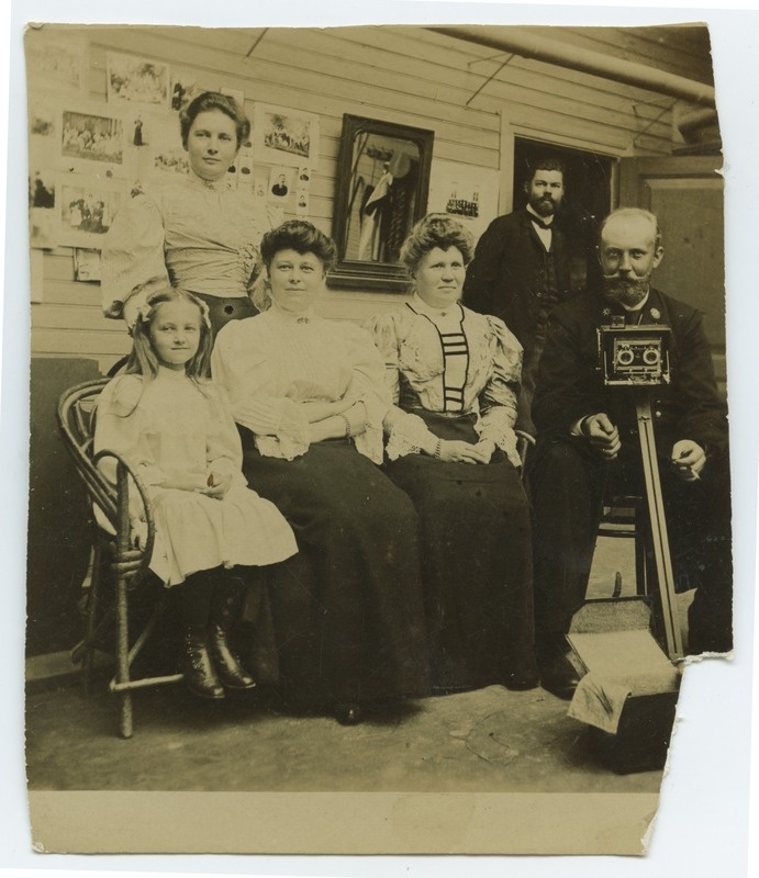 Ühe päevapiltniku ateljees. Pildil grupp inimesi ja fotograaf oma aparaadiga