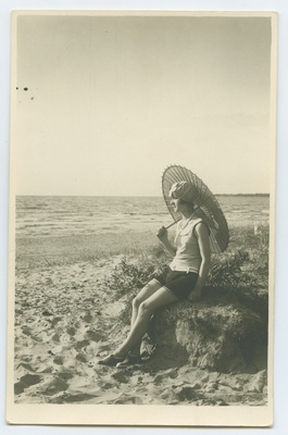 Mere ääres rannaliival  päikesevarjuga, trikoos, naine.  duplicate photo